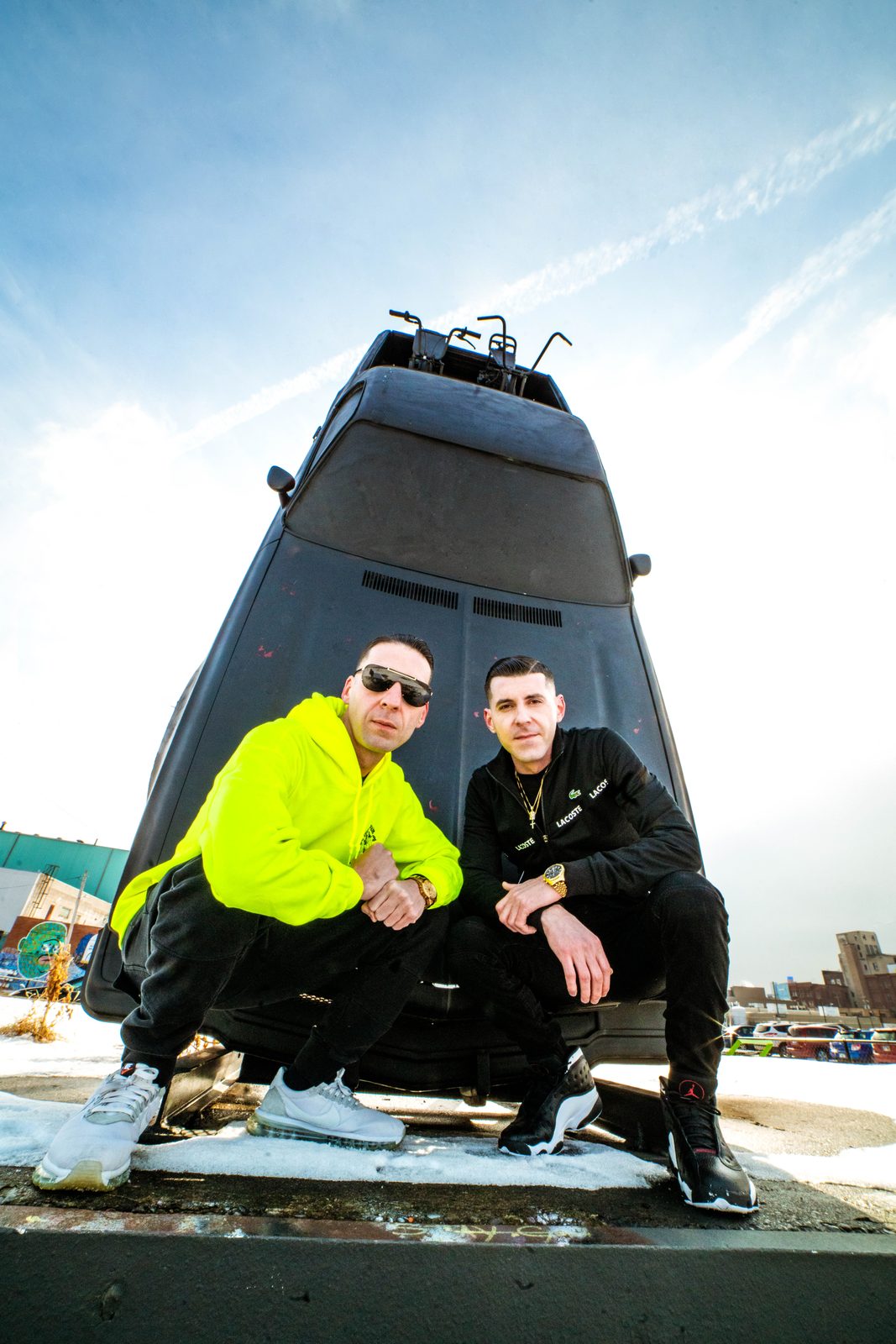 KING T and LUSS crouched in front of a tour bus