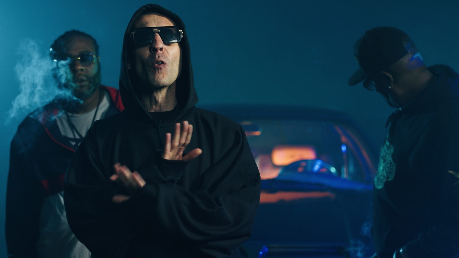 KING T in a hoodie on a music video set in blue haze