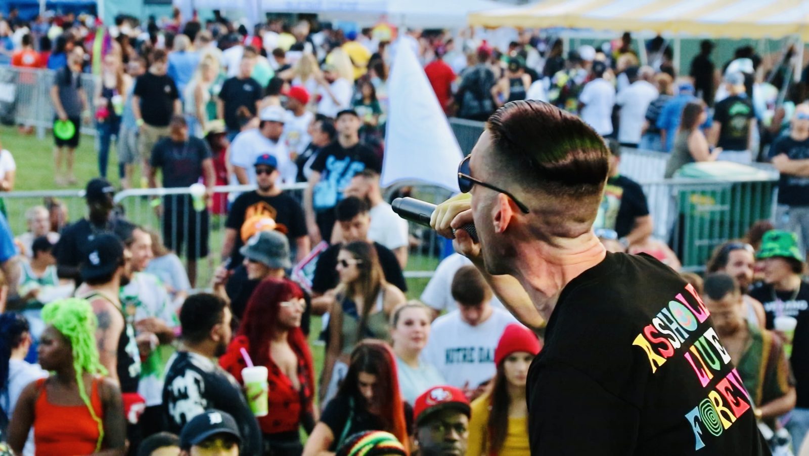 A TNL performer on stage above a packed festival crowd