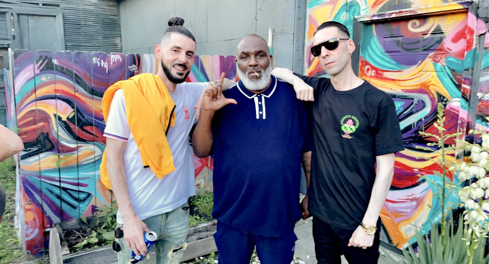 KING T and LUSS with a fellow artist in front of a colorful mural